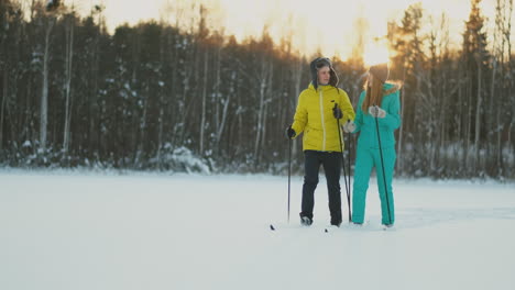 A-man-in-a-yellow-jacket-and-a-girl-in-a-blue-jumpsuit-skiing-in-slow-motion-at-sunset